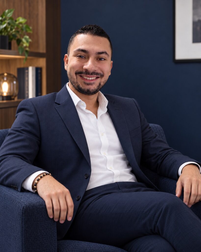 Franco Daniel Valencia Marín con traje azul marino, sentado y relajado en un sillón de despacho